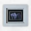 Small tonal oil painting of a reclining nude in cool blue and grey against black, in a pale frame, by Julie Tugwell.